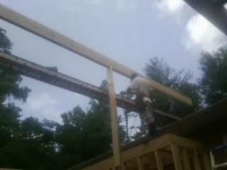 Carpenter setting a ridge beam over a new addition frame — Ice Dam Removal by Roofing Brothers in Dobbs Ferry