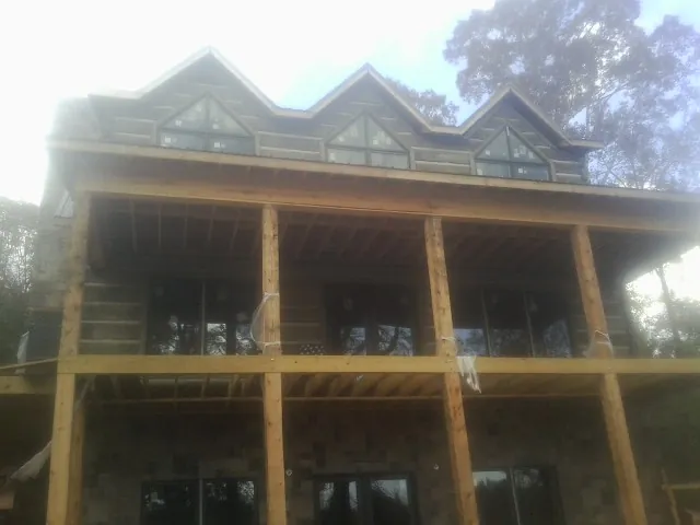 Dormers and porch framing on a large log home under construction — Roof Coating work by our crew in Dobbs Ferry