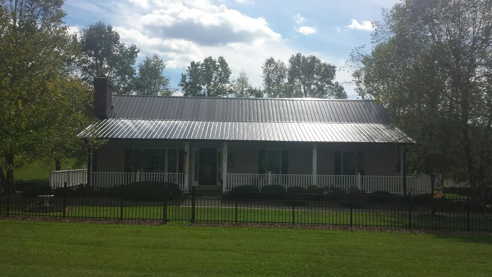 Gray metal roof on a brick ranch with a full width front porch — Gutter Guard Installation work by our crew in Dobbs Ferry