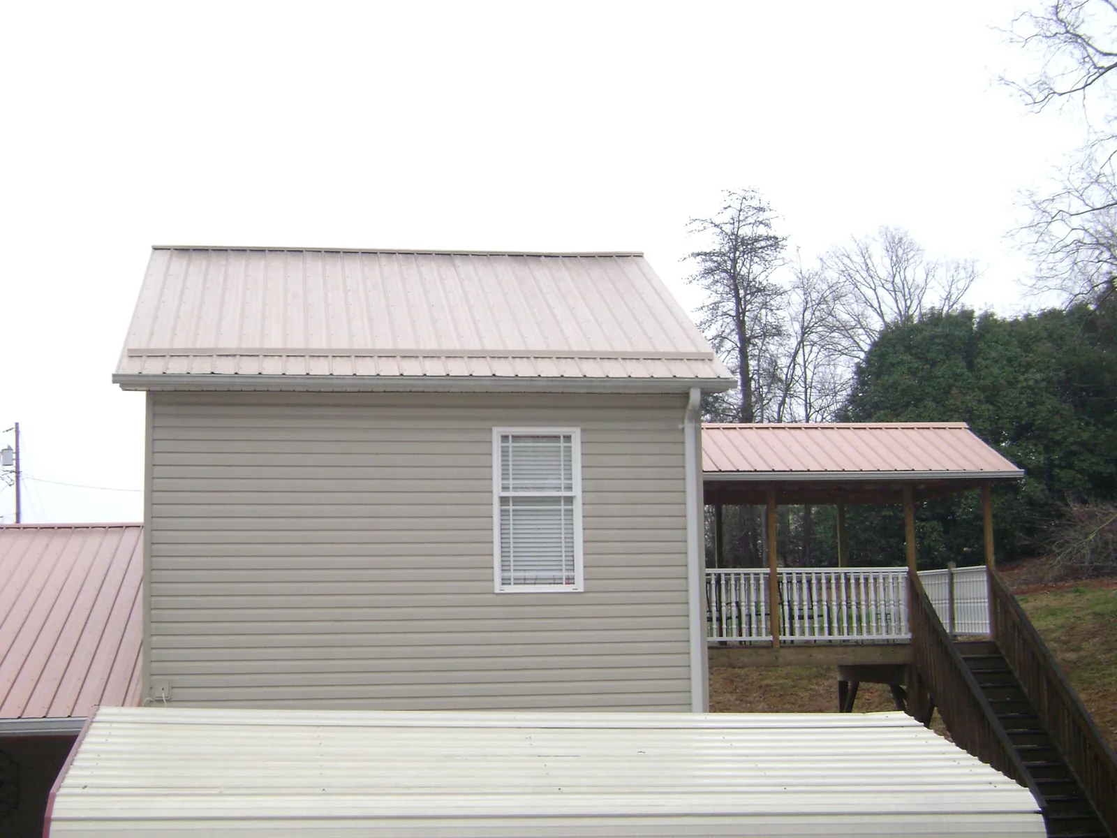 Tan metal roofs on a two story addition and attached porch, from a Roof Replacement job in Dobbs Ferry