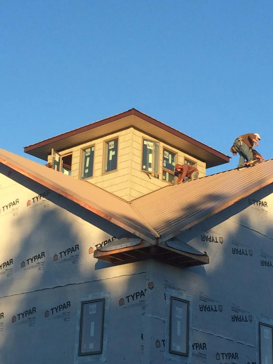 Roofers working around a rooftop cupola on a new metal roof at sunset — Roof Waterproofing in Dobbs Ferry by Roofing Brothers